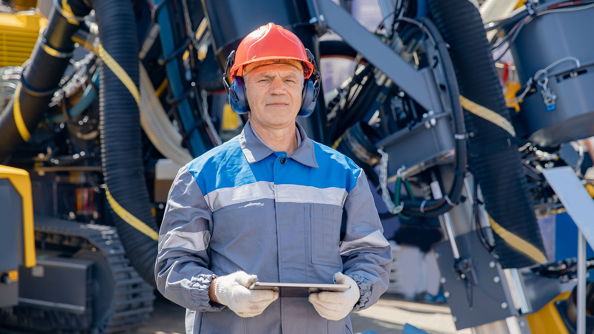 tier 1 oil worker in orange hard hat holding ipad